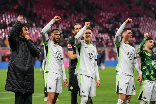 Lukas Nmecha (left), Mattias Svanberg (center), and Joakim Maehle (right salute the Wolfsburg traveling support. 