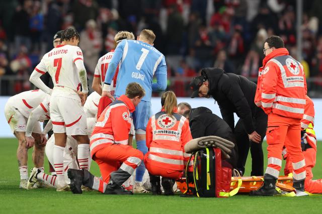 Leipzig players and medical staff gather around Benjamin Henrichs on the Allianz Arena pitch last night.